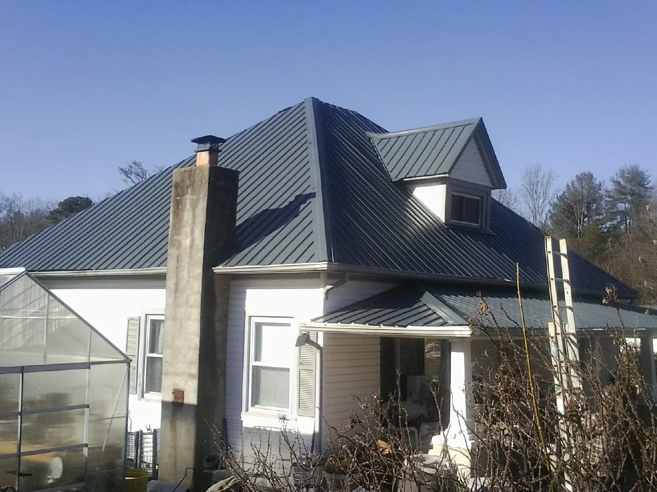 Dark blue standing seam metal roof on a white farmhouse with dormer — Slate & Tile Roof Repair by Roofing Brothers in Startex