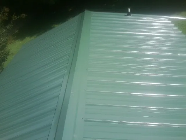 New green metal panels meeting at the ridge of a roof — Flat Roof Repair work by our crew in Startex