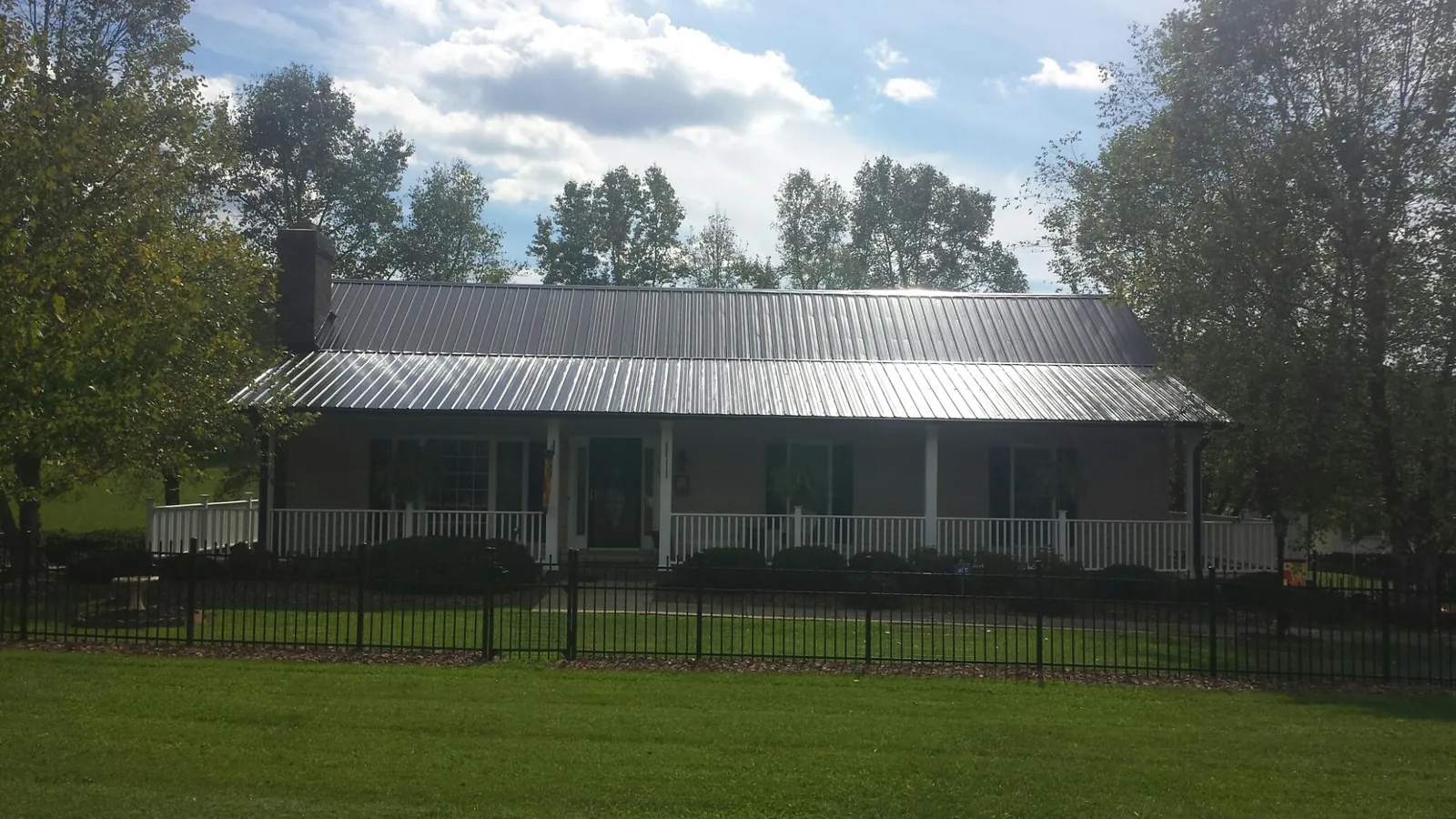 Gray metal roof on a brick ranch with a full width front porch — Gutter Guard Installation work by our crew in Startex