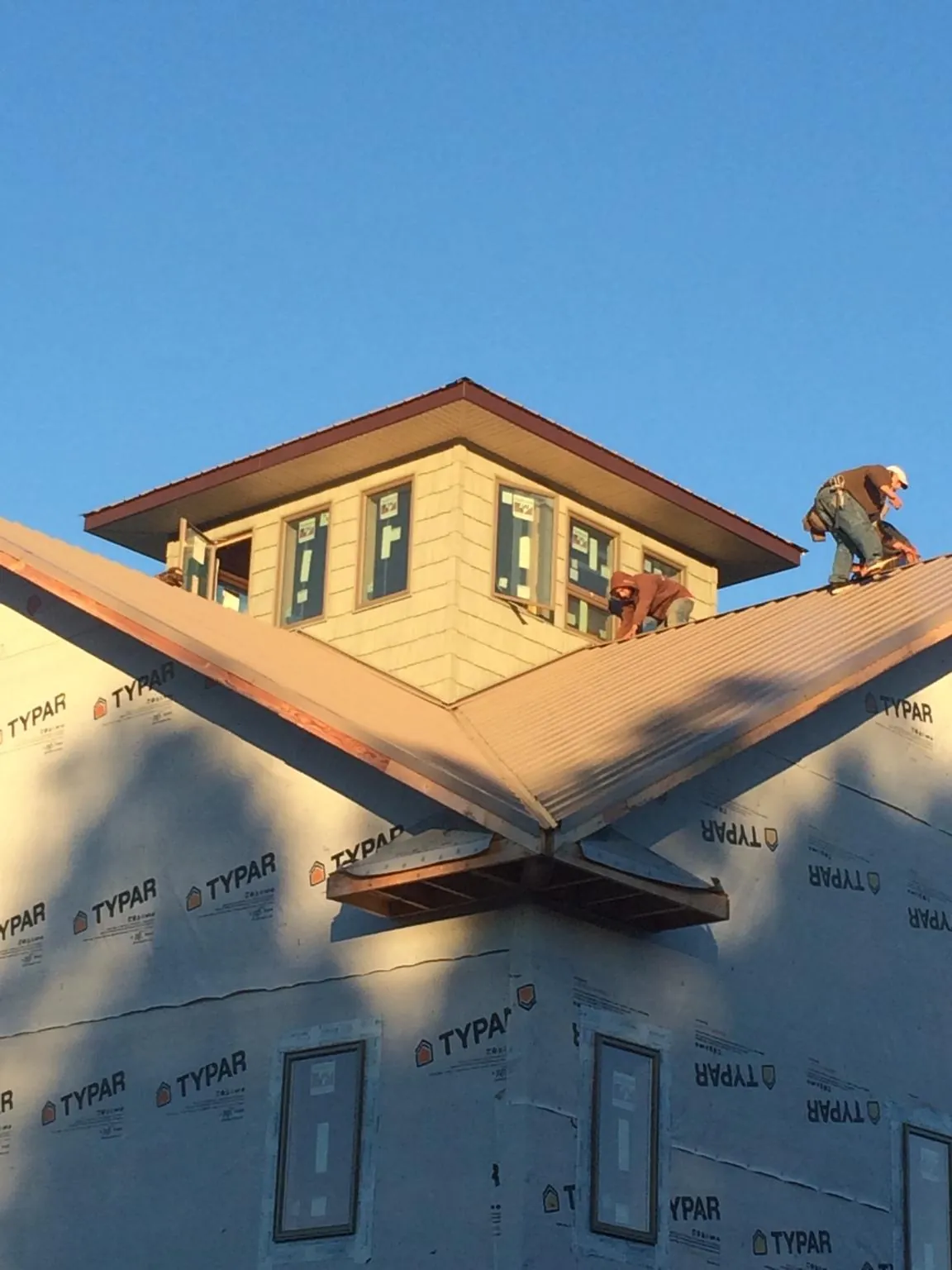 Roofers working around a rooftop cupola on a new metal roof at sunset — Roof Waterproofing in Startex by Roofing Brothers
